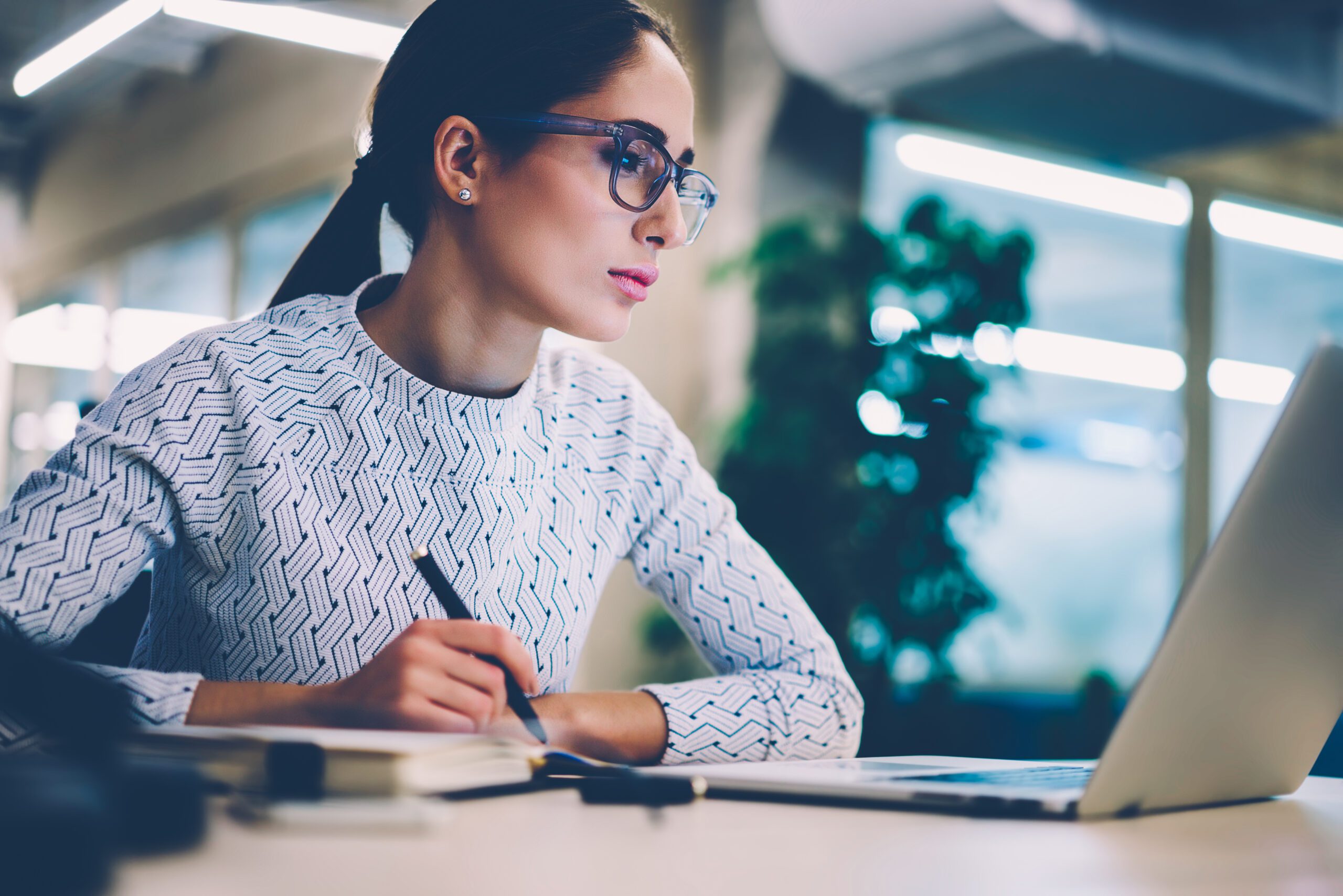 Concentrated businesswoman analyzing information from networks reading news from netbook sitting at desktop,female employee checking email box planning project strategy using modern technologies